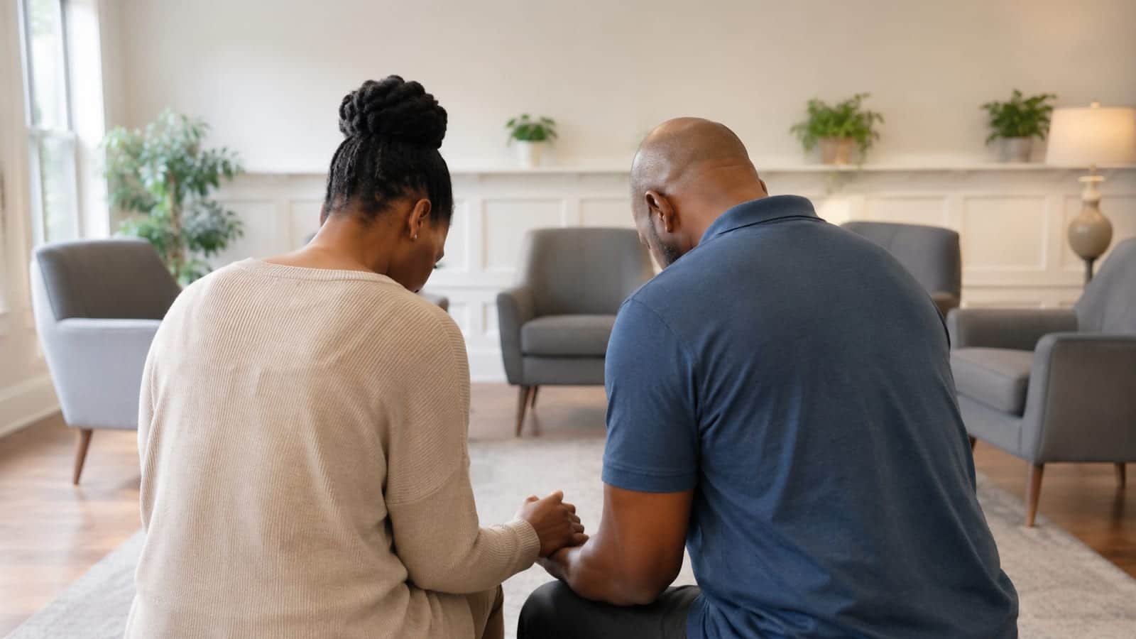 Mentor and learner praying together quietly, viewed from behind in a bright fellowship room