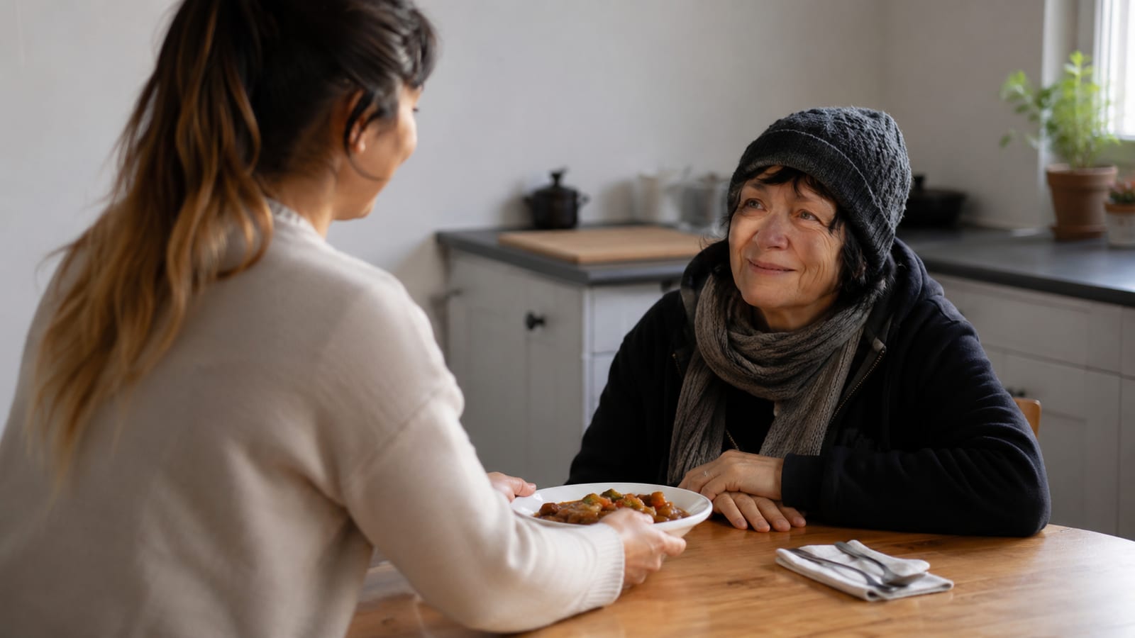 Hands offering a warm meal across a simple table during everyday Christian service