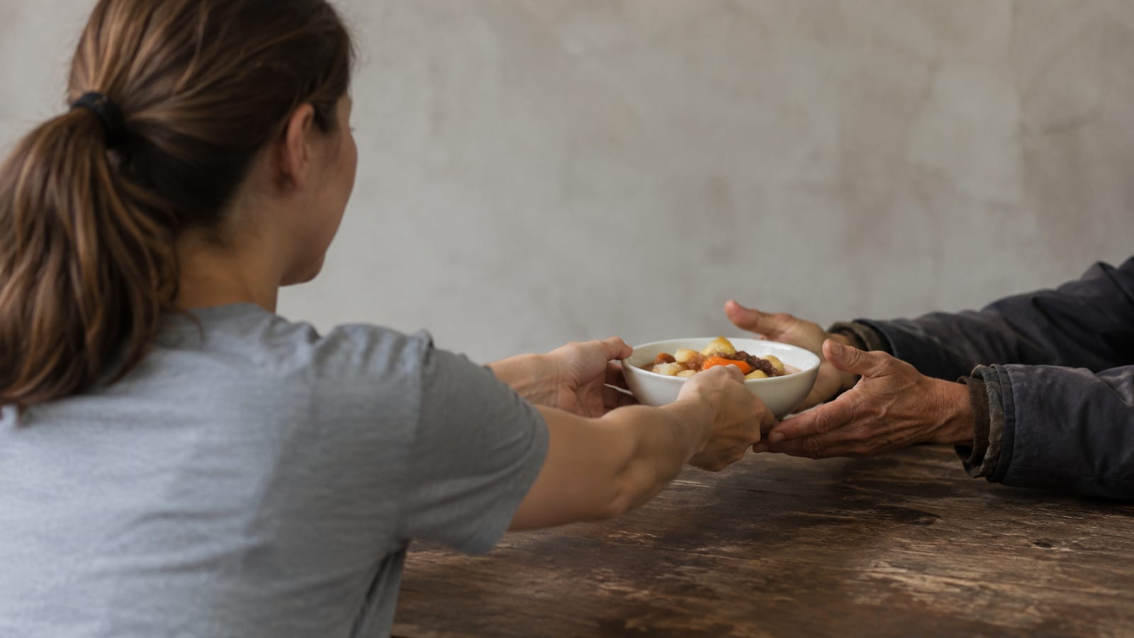 Volunteer offering a warm meal to an unseen neighbor without expecting recognition or repayment